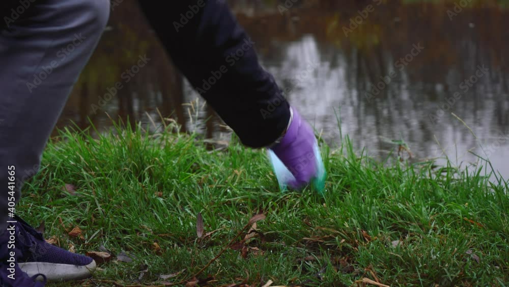 a man picks up a mask thrown by the river. cleanliness and order concept a man picks up a mask thrown by the river. cleanliness and order concept