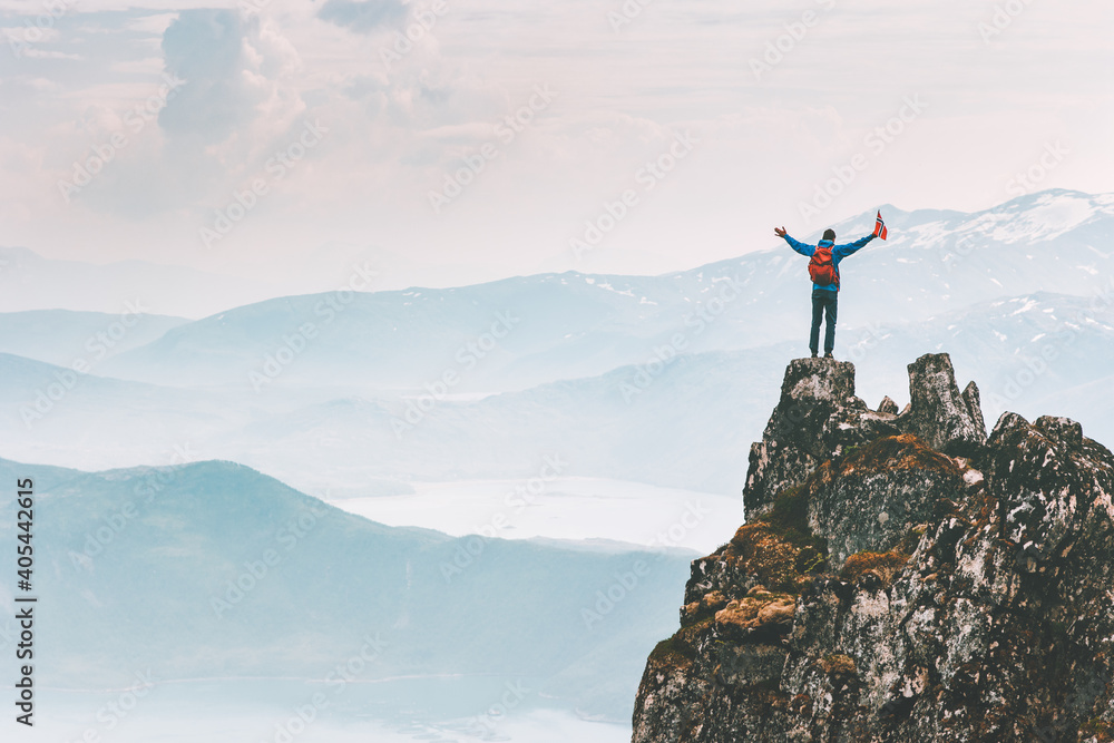 Fototapeta premium Man climber on mountain cliff summit traveling hike in Norway adventure vacations outdoor extreme activity healthy lifestyle traveler success raised hands Husfjellet peak