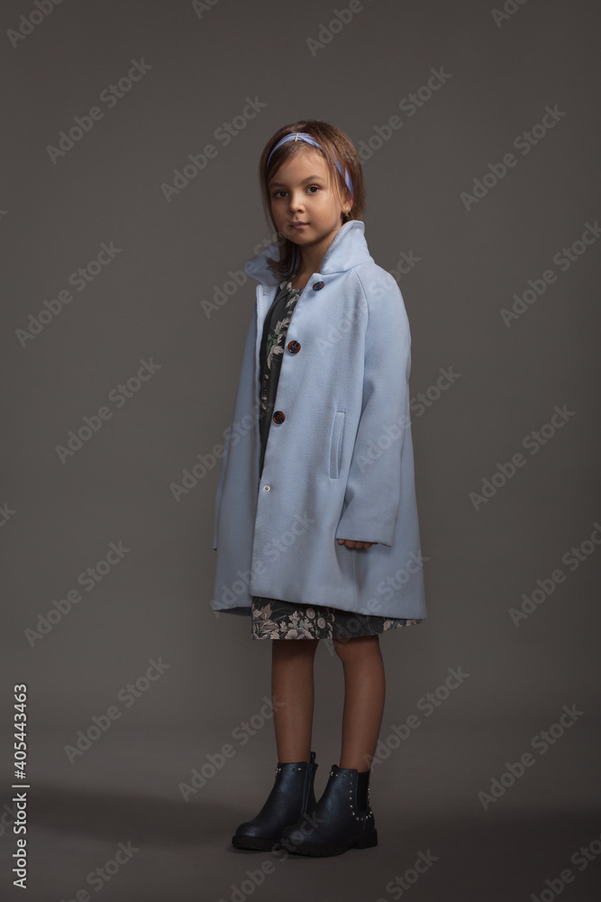 Beautiful little girl in a blue stylish coat and a blue headband on her hair Beautiful little girl in a blue stylish coat and a blue headband on her hair