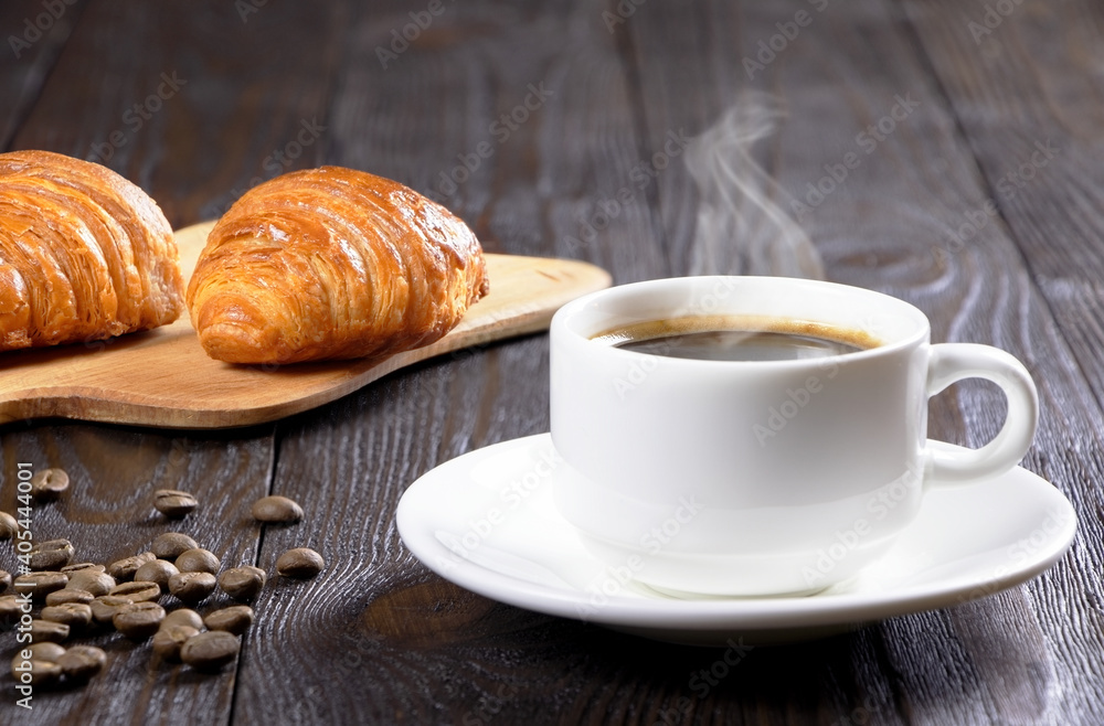 A cup of hot coffee and croissants on a wooden background. Breakfast with coffee and fresh pastry. Copy space. Fresh cake and pastry A cup of hot coffee and croissants on a wooden background. Breakfast with coffee and fresh pastry. Copy space. Fresh cake and pastry