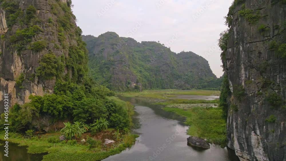 Aerial shot of beautiful limestone mountains with passes carved by a river in Ninh Binh region, a famous tourist destination in northern Vietnam. Travel to Vietnam concept Aerial shot of beautiful limestone mountains with passes carved by a river in Ninh Binh region, a famous tourist destination in northern Vietnam. Travel to Vietnam concept