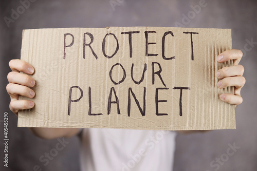 hands holding a cardboard poster with an inscription save our planet