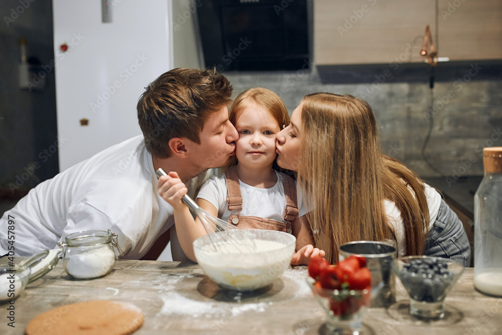 A full multiethnic family with a charming daughter gathered in a modern kitchen, whole child and hugs. Making cake mix, stir up the dough, enjoy socializing and culinary hobbies A full multiethnic family with a charming daughter gathered in a modern kitchen, whole child and hugs. Making cake mix, stir up the dough, enjoy socializing and culinary hobbies