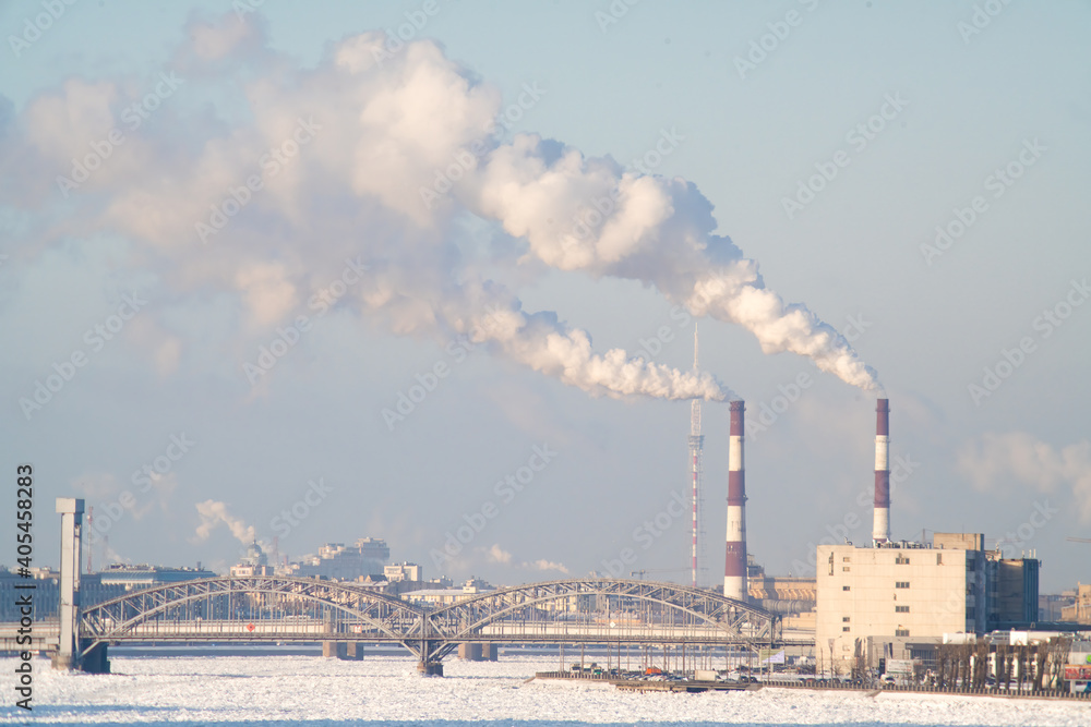 City view with smoking chimneys. A bridge and a frozen river.