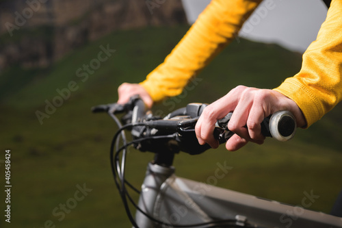 Close-up of female hands holding the handlebars of a mountain bike in the summer in the mountains