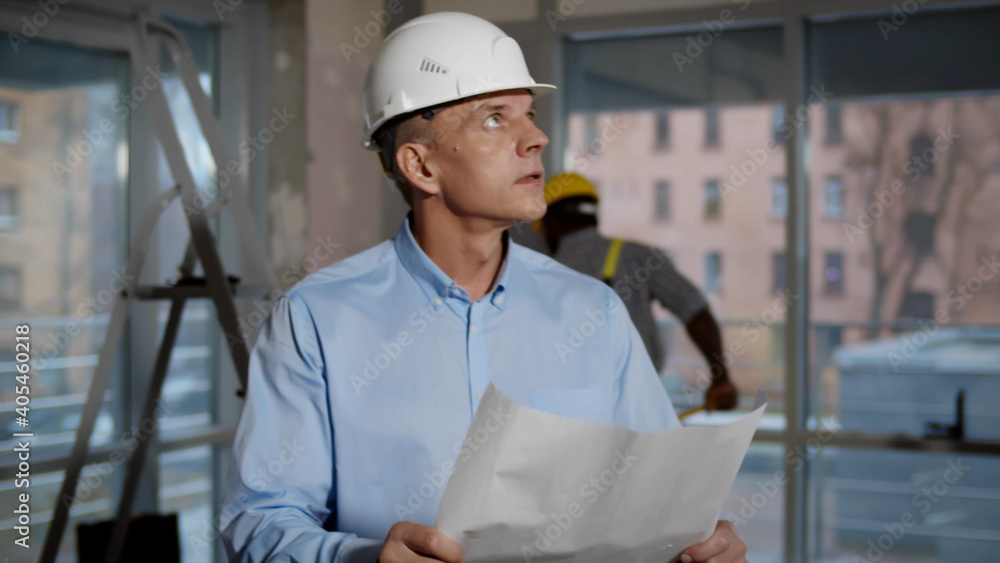 Engineer wearing safety helmet looking at blueprint on construction site Engineer wearing safety helmet looking at blueprint on construction site