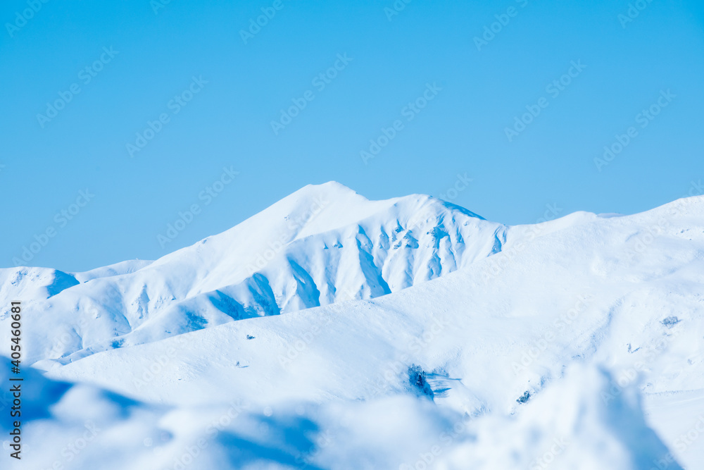 Snow-capped rocks and clear blue sky. The sun shines, which gives brightness.