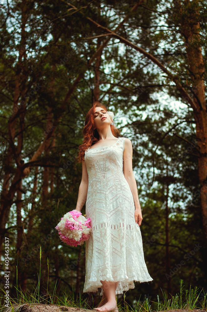 Outdoor portrait of young redhead woman in vintage wedding dress with big bouquet of pink peonies. Woman's Day. Female spring, summer fashion concept. Wedding day.