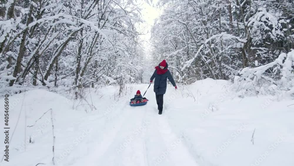 mom and son ride tubing in a winter frosty forest aerial view mom and son ride tubing in a winter frosty forest aerial view