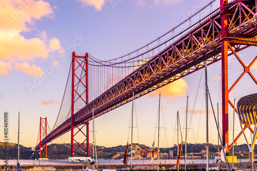 Barcas amarradas en el puerto bajo el Puente colgante 25 de abril sobre el tajo en Lisboa al atardecer