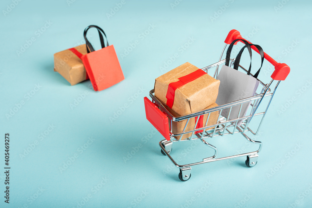  A miniature shopping cart filled with a yellow box and bag.