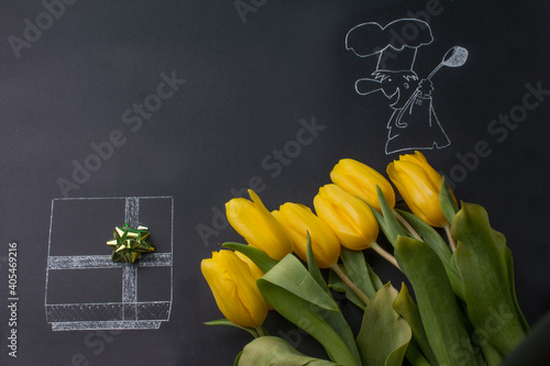 black board with a pattern and yellow tulips. Gift box and scullion