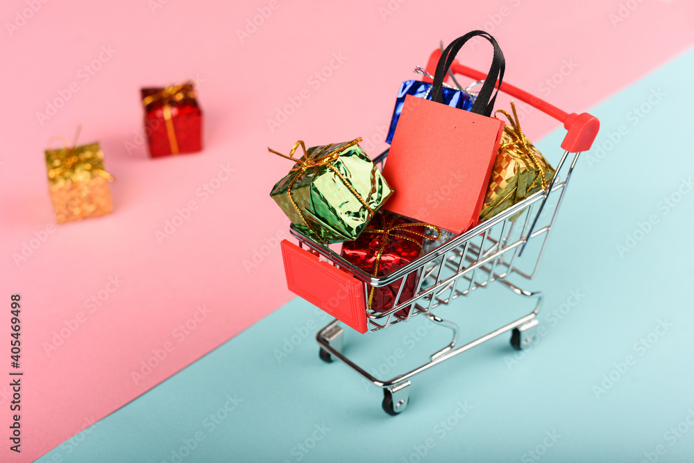 : A miniature shopping cart filled with many gift boxes and bags.