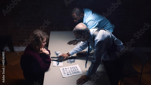 Konstfotografi Diverse detective interrogating scared arrested woman and threatening with gun