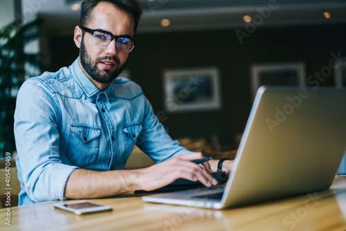 Pensive man browsing laptop working in modern workspace