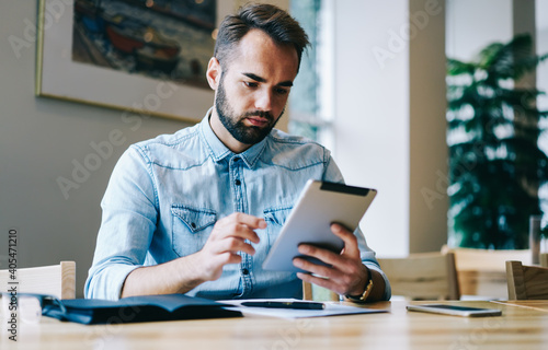 Thoughtful entrepreneur using tablet in modern workspace