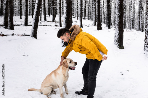 Young man playing with his dog at a snowy mountain
