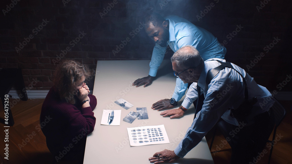 Two police officers and woman criminal in interrogation room - obrazy, fototapety, plakaty 