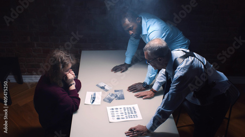 Two police officers and woman criminal in interrogation room photo