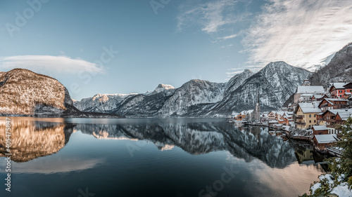 Panorama view of snowy village Hallstatt by lake at foot of snow mountain with clear sky in winter in Austria