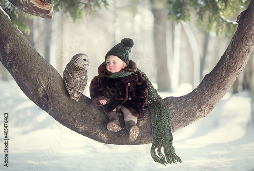 Little cute boy with owl sitting on the curved tree. Image with selective focus and toning.