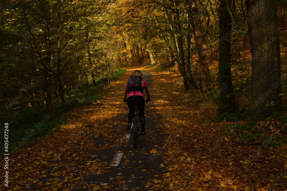 Woman cycling through autumn forest