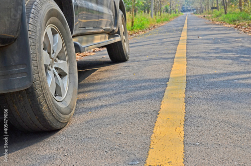 Black vehicle on asphalt road with yellow line in the forest