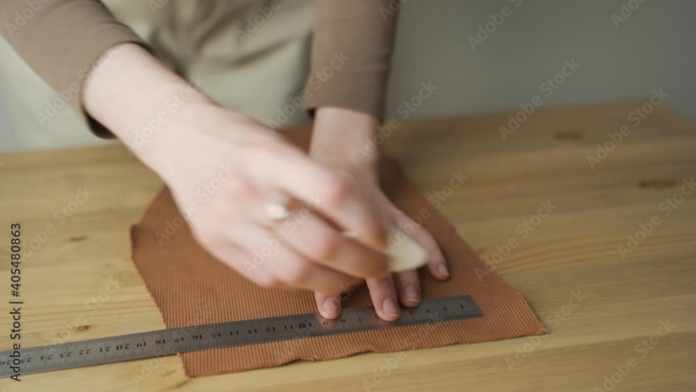 Close up of artisan hands measuring, marking, and cutting fabric material Close up of artisan hands measuring, marking, and cutting fabric material