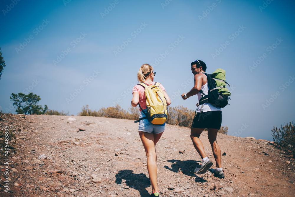 Traveling couple walking on empty road with backpacks Traveling couple walking on empty road with backpacks