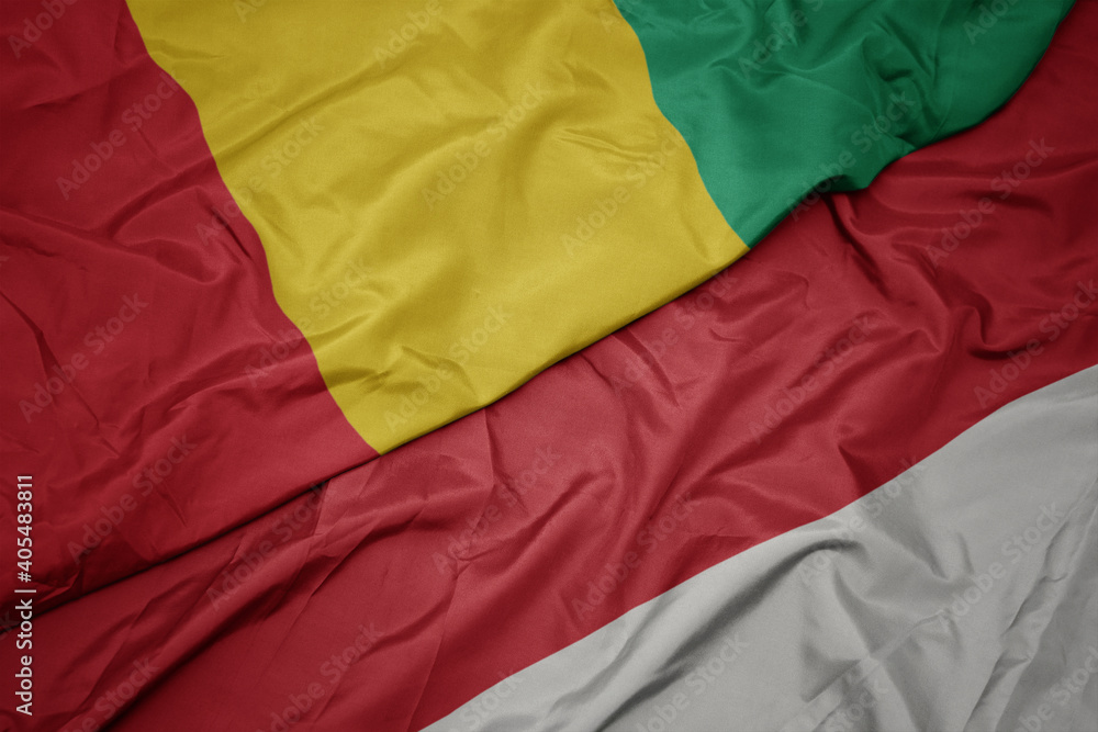 waving colorful flag of indonesia and national flag of guinea.