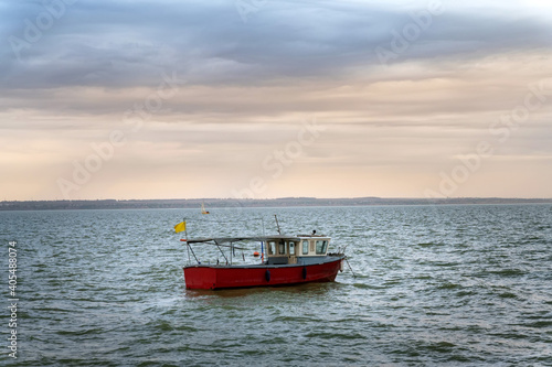 Photo of motor fishing boat under dark clouds with yellow flag photo