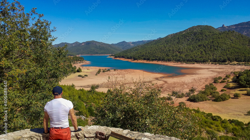 young man looking at a lake from a lookout point