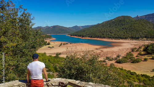 young man looking at a lake from a lookout point