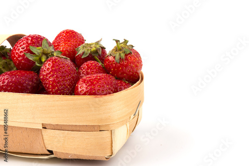 Fresh red strawberries in wooden basket on white background. Agriculture and ecological fruit farming concept.