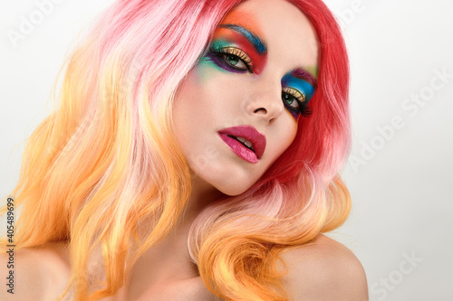 Beauty Fashion woman with Colorful Bright Art Makeup, Pink Dyed Hairstyle. Girl with blue eyes, stylish hair, make up. Beautiful model portrait, fashionable color trend creative make-up.