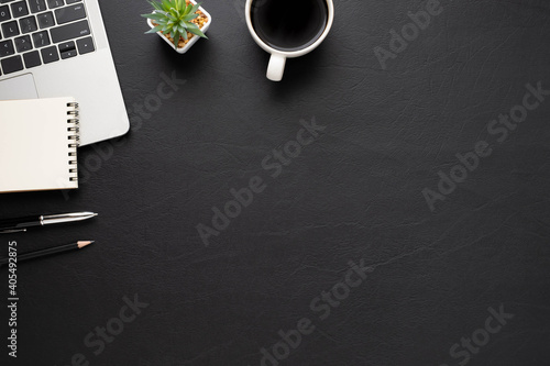 Top view above of Black leather office desk table with keyboard, notebook and coffee cup with equipment other office supplies. Business and finance concept. Workplace, Flat lay with blank copy space.