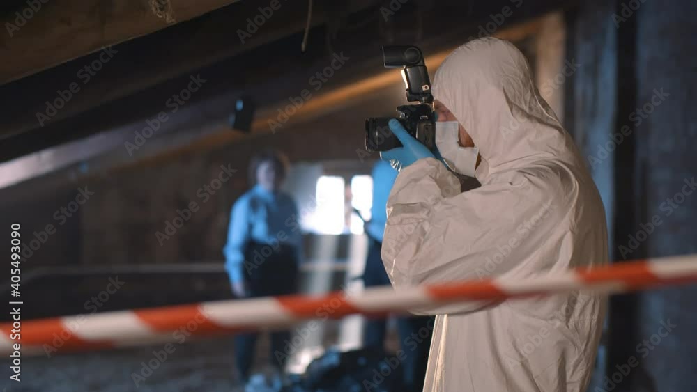 Forensic specialist with photo camera standing at crime scene Forensic specialist with photo camera standing at crime scene