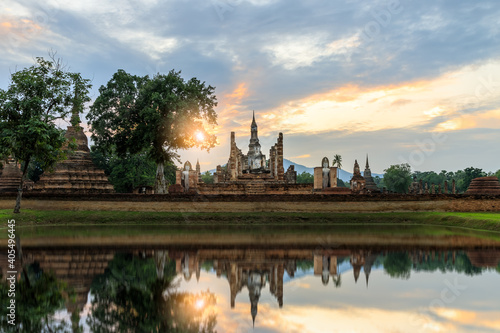 Buddha statue and pagoda Wat Mahathat temple with reflection during sun set  Sukhothai Historical Park  Thailand
