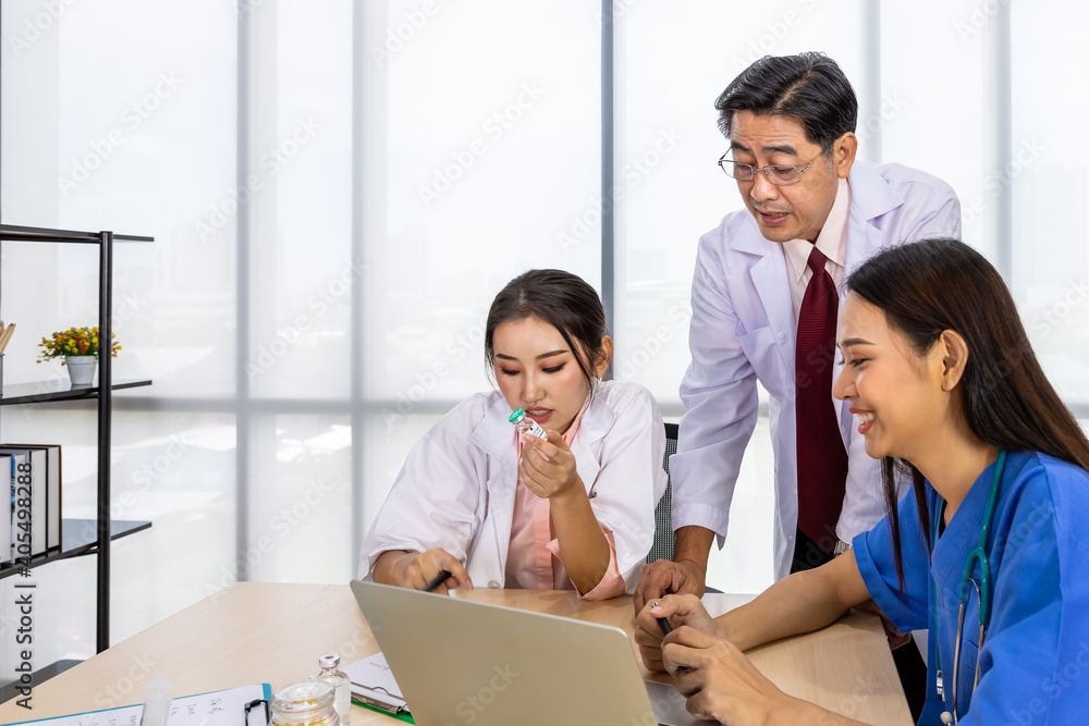 Asian male and female medical doctor team sitting at desk and meeting discussion about vaccine with laptop computer Asian male and female medical doctor team sitting at desk and meeting discussion about vaccine with laptop computer