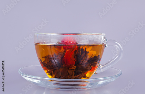 Exotic green flower tea in a glass cup on a gray background.