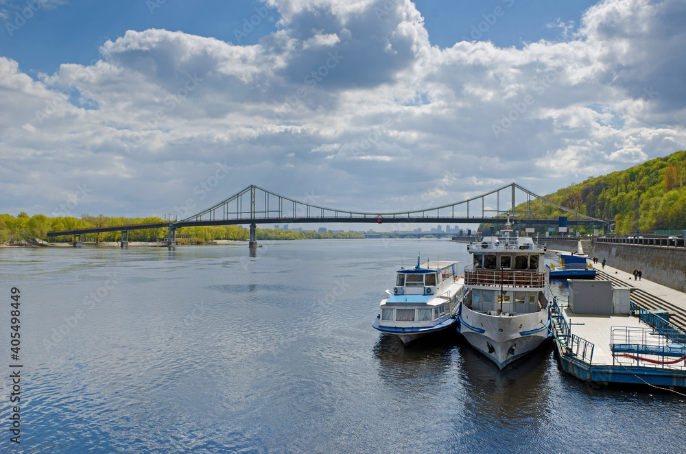 Footbridge Dnipro river panorama embankment with tourist boats Kyiv Ukraine