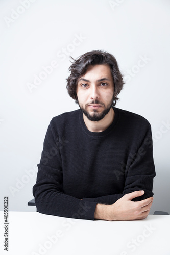 Φωτογραφία Portrait shot of an adult middle eastern man wearing black sweater leaning on a table with confident facial expression