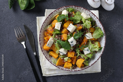 Salad with quinoa, pumpkin and Dor Blue cheese in a plate on a dark background. View from above