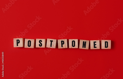 Postponed - words from wooden blocks with letters, postponed concept, top view background.