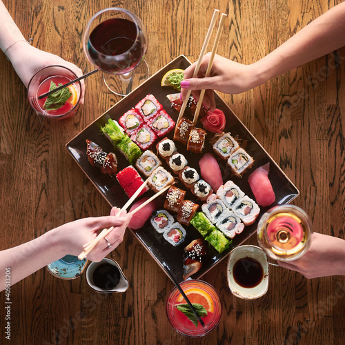 Top of view. Two girls are eating sushi. Set of various types of rolls and sushi with drinks