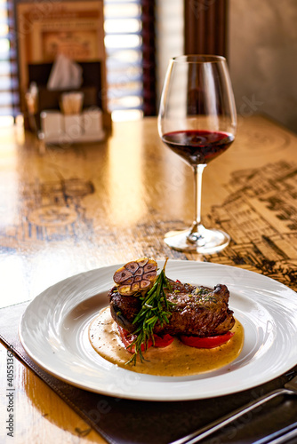 Juicy beef steak with a glass of red wine on a table in a restaurant