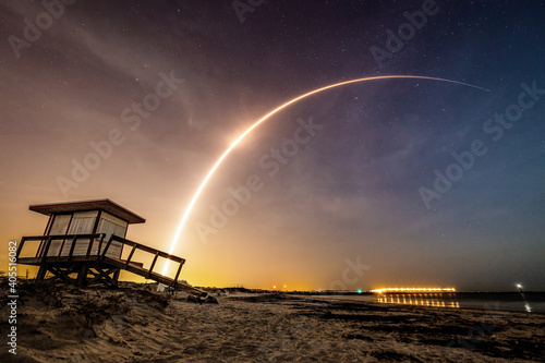 Fototapeta Naklejka Na Ścianę i Meble -  Rocket streaks above the Beach at Night though the Stars