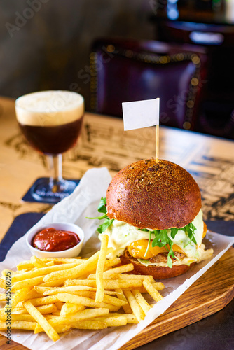 Juicy beef burger, French fries and a glass of light beer in a restaurant