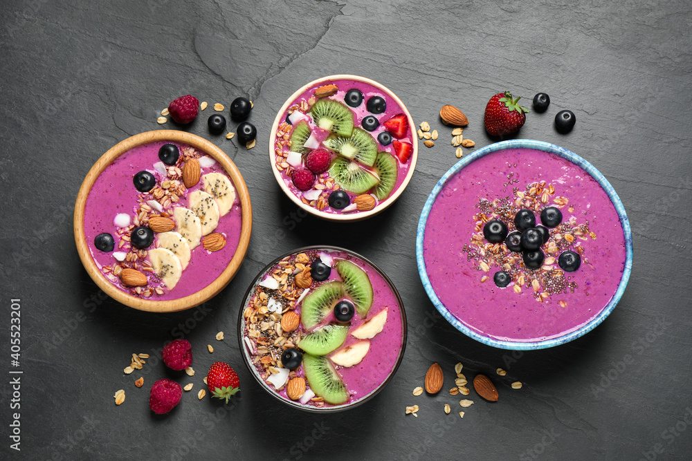 Acai smoothie bowls with granola and fruits on black table, flat lay