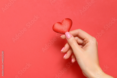 Valentine's day concept. A young girl holds a heart in her hand on a red background. Copy space.